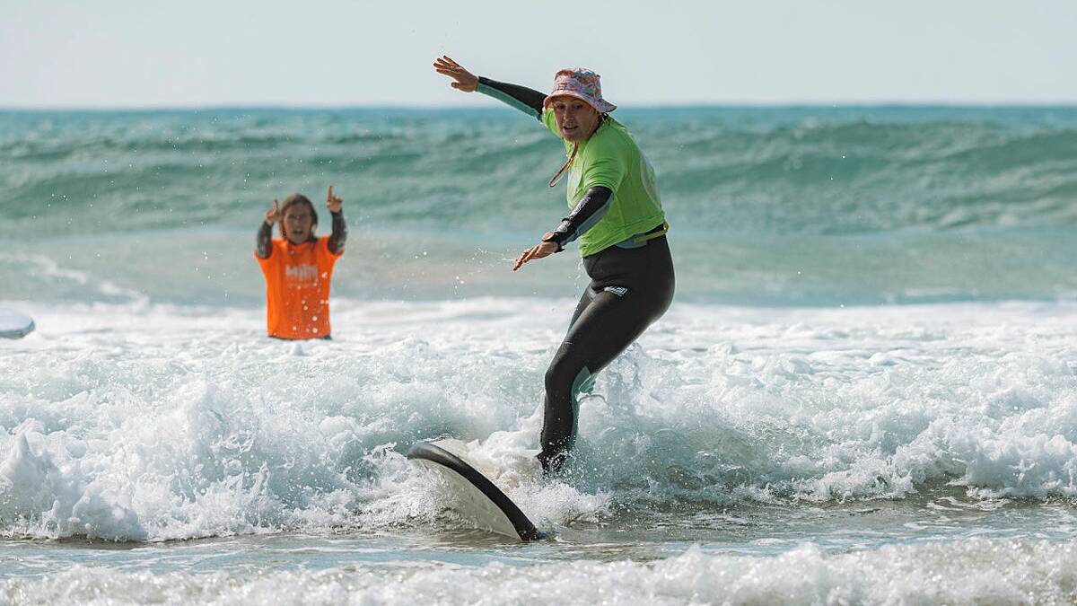 Former world surfing champion, Pam Burridge, cheers on as Leading Aircraftwoman Kobey Misios rides a wave during the Australian Defence Force women's surf development camp in Ulladulla. Picture by ABIS Jasmine Moody.