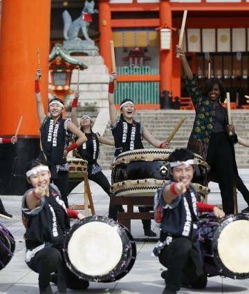 U.S. first lady Michelle Obama (C) beats a Japanese traditional taiko drum with members from Akutagawa High School Taiko Club in front of the main gate, as she visits Fushimi Inari Shinto Shrine in Kyoto, western Japan March 20, 2015. Michelle Obama flew in to Japan on Wednesday for a three-day visit as part of the Let Girls Learn international girls education initiative. REUTERS/Issei Kato            TPX IMAGES OF THE DAY Photo: ISSEI KATO