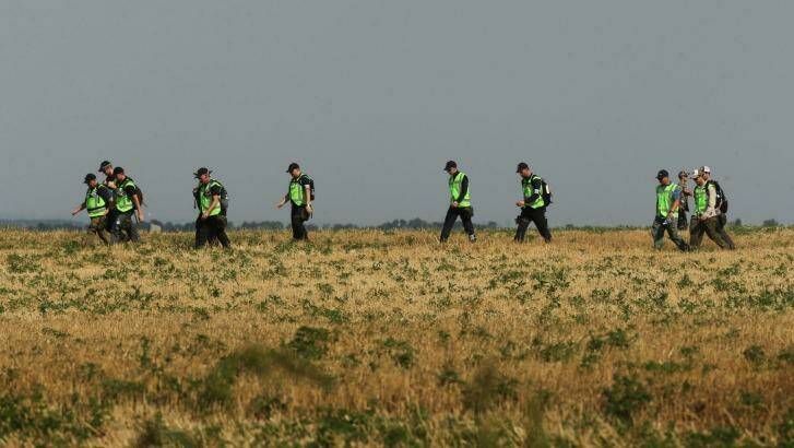 Australian and Dutch police walk across a field during their search last month for remains of victims of MH17. Photo: Kate Geraghty