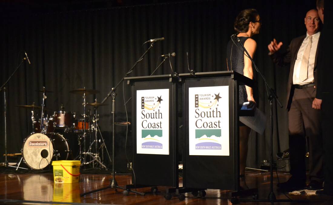 DRIPPING: Shoalhaven City Council corporate and community services manager Craig Milburn helps presenters move the lectern and placed buckets on the stage when the $11 million Ulladulla Civic Centre roof began leaking during the South Coast Tourism Awards on Wednesday night.