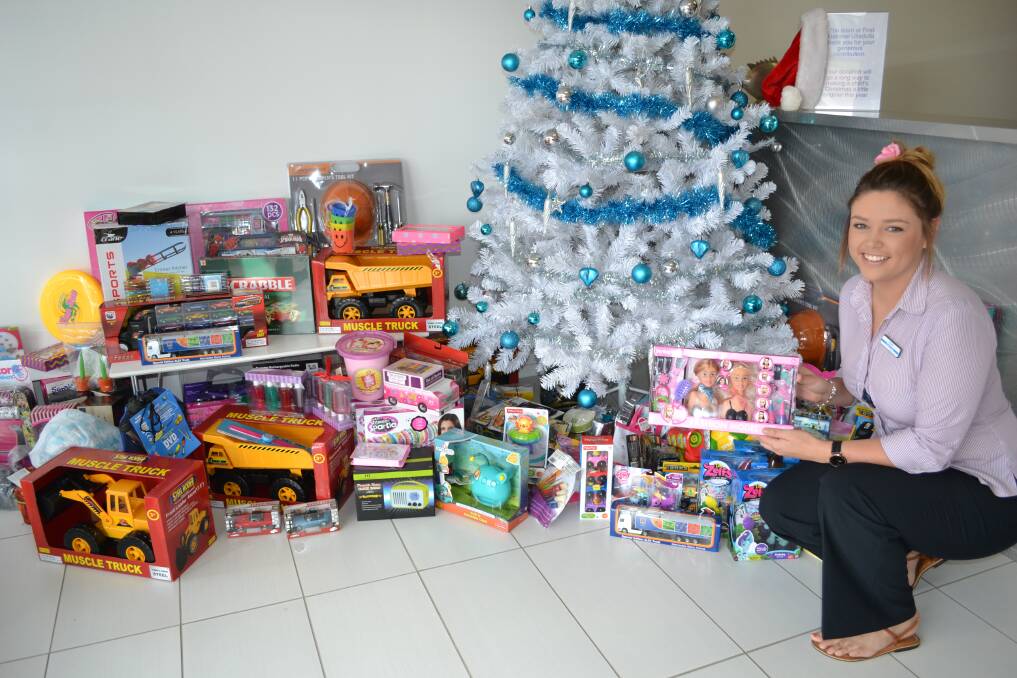 GIVING: Leigha Clough puts a gift in the First National Real Estate Ulladulla Giving Tree. 