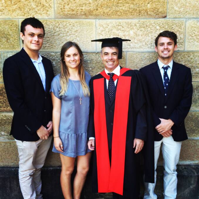BRINGING IT HOME: Milton pharmacist Dr Stephen Carter, pictured at his graduation with three of his four children Henry (left), Sally and Hugh, is spending most of his time in Sydney, but still enjoys his weekends at home in Mollymook. 