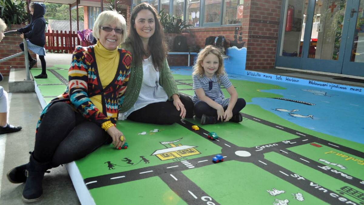 FUN PLAY: Christine Cook and Liz Craig play with Ulladulla Public School student Casey Ginns at the new mural located on the school grounds. 