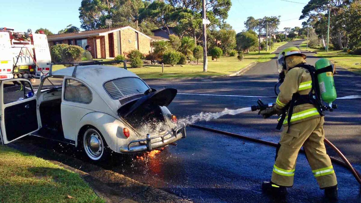 BURNT: Fire fighters extinguish the flames from the engine of Roz Johnston’s VW beetle.