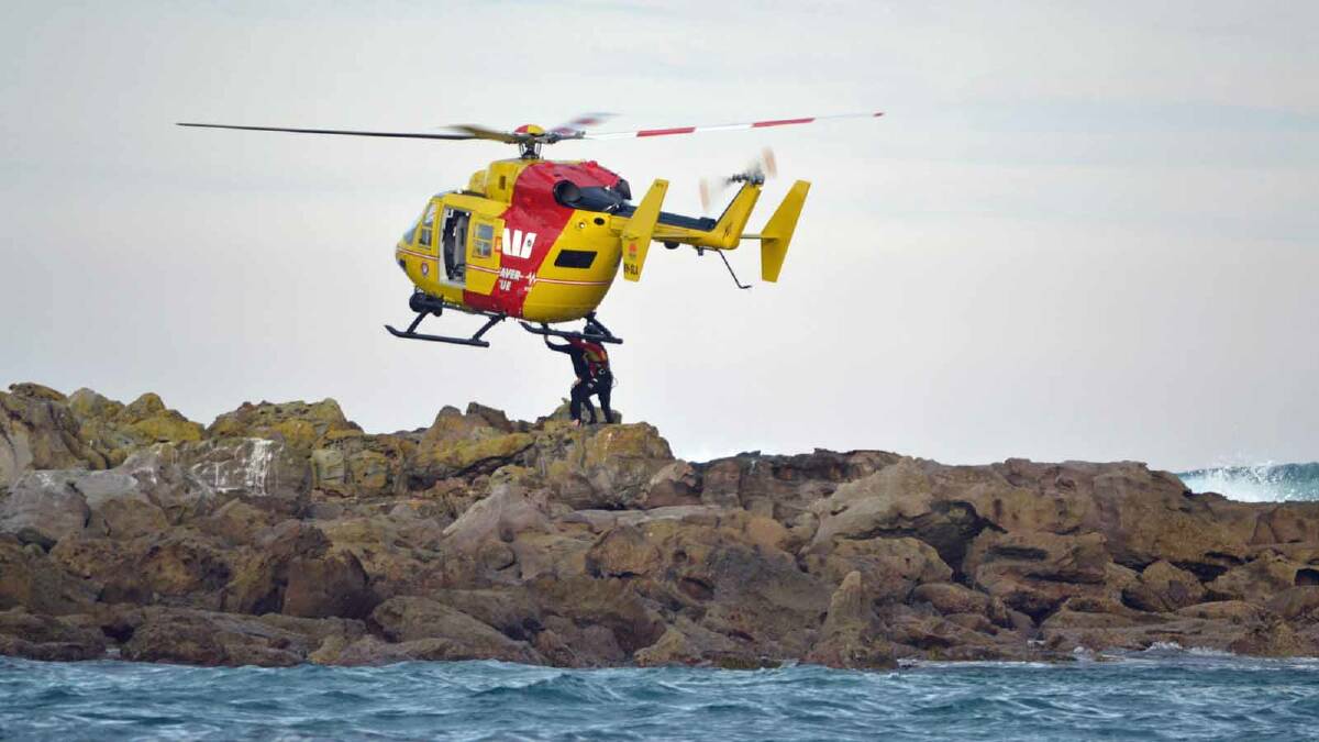 RESCUED: A father and his daughter climb onto the rescue helicopter after they were stranded on rocks off North Narrawallee on Friday.