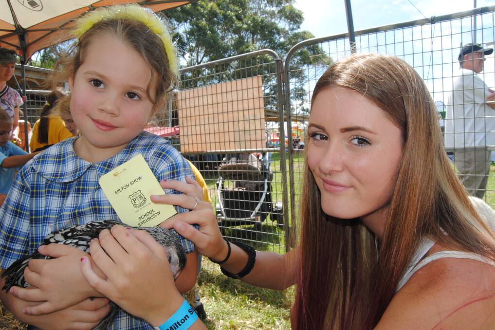 Bella Fernandez gets a helping hand from Victoria Spry while handling a chook in the animal nursery.