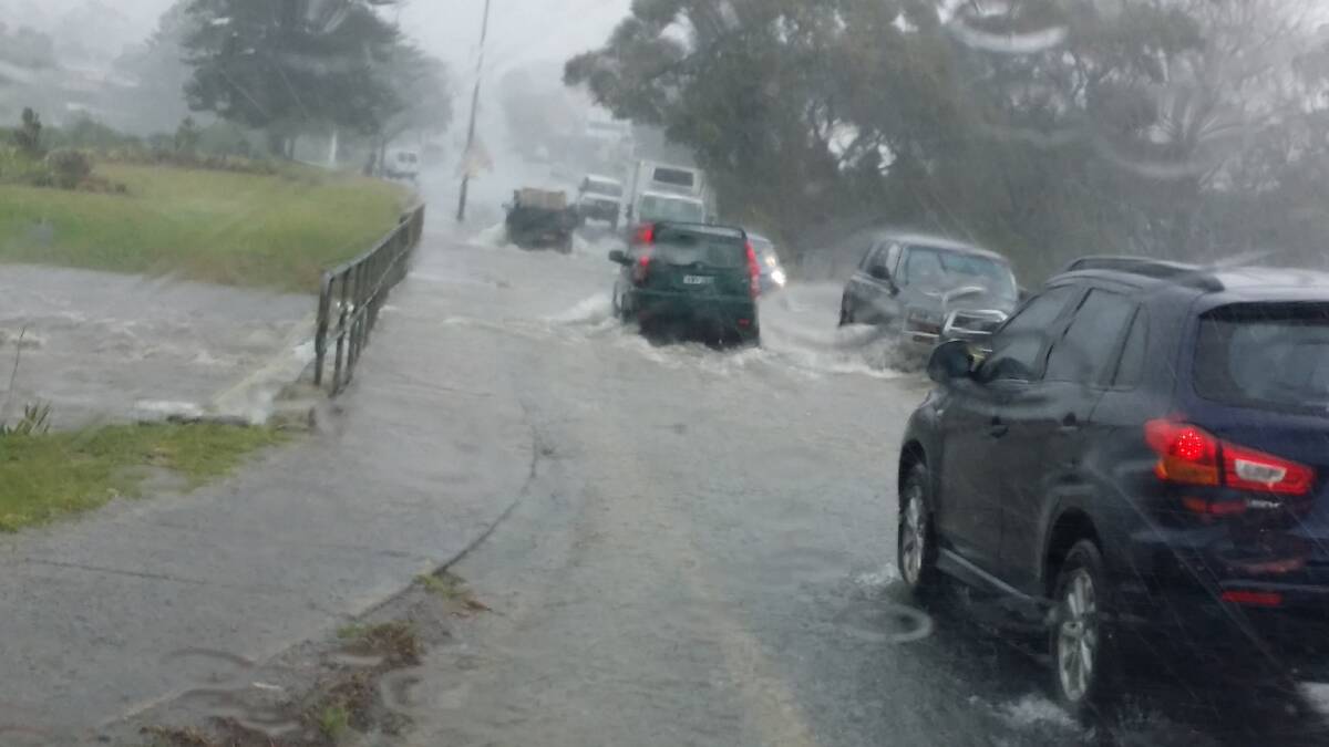 Floodwater flows across the Princes Highway in Ulladulla yesterday. Picture: CHRIS CHANNELLS