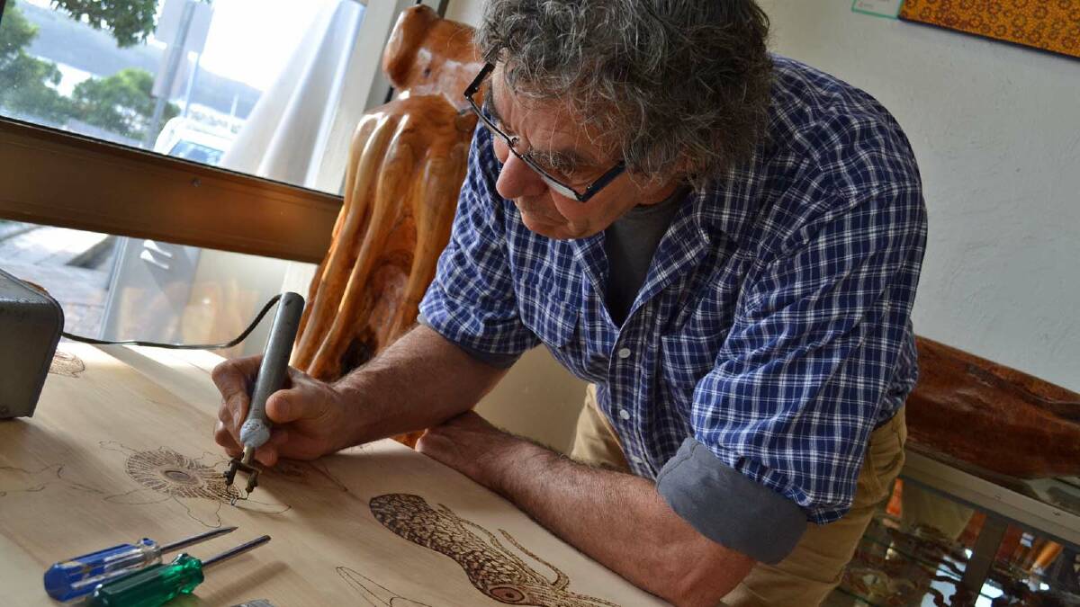 FREE STYLER: Noel Butler concentrates as he burns an image of a turtle into a timber table top at his Ulladulla café and gallery. INSET: An example of Noel’s work