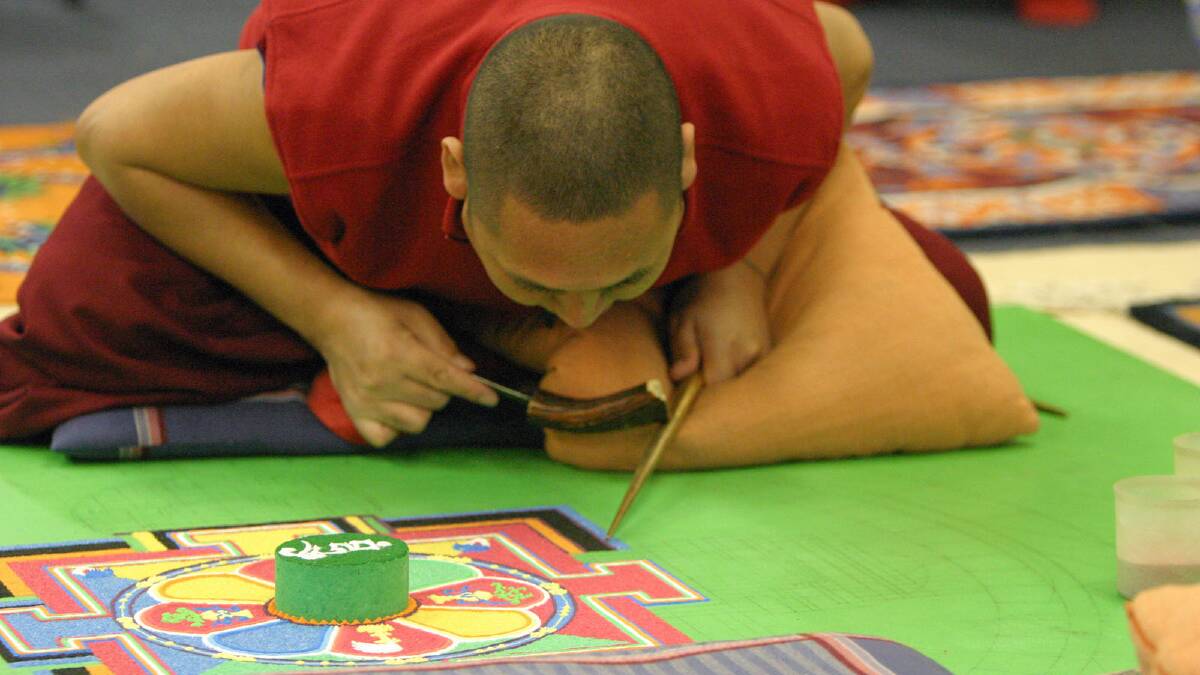 SANDS OF TIME: A Tibetan monk prepares a sand mandala while working in the Ulladulla Civic Centre during a previous visit to the region in 2009. Picture: STUART CARLESS