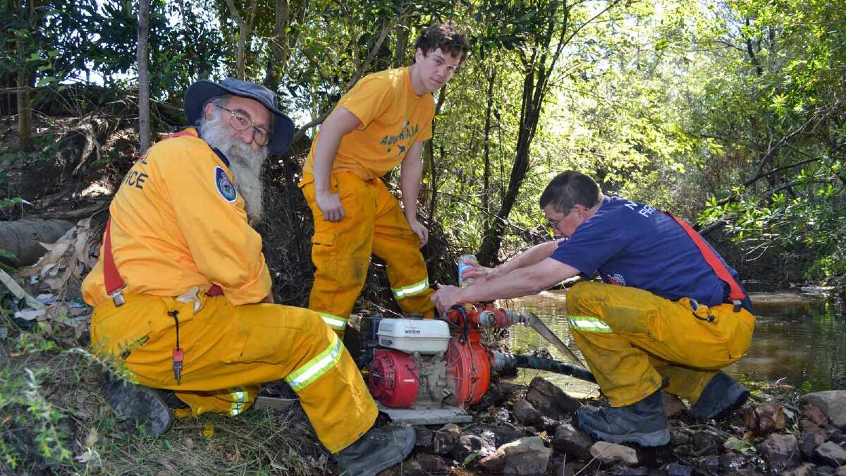 TOP UP: Firefighters from Culburra Beach brigade, Bob, Burton, Matt Crowe and Brian Perry use a mobile pump in a creek to refill their tanker on the Wandandian fire ground.