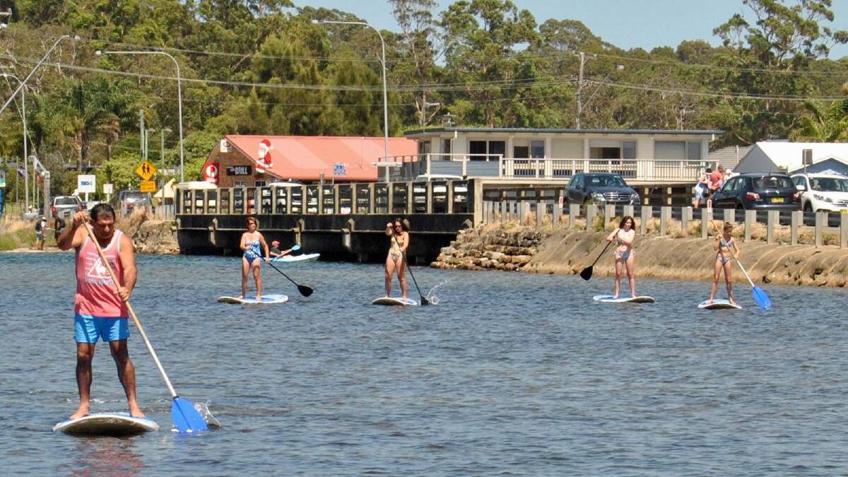 ON THEIR FEET: Taking to paddleboards on Burrill Lake are visitors from Windsor, Canberra and Sydney – Frank, Amanda and Andrea Baldacchino, Danielle Clarke and Grace Coulton.