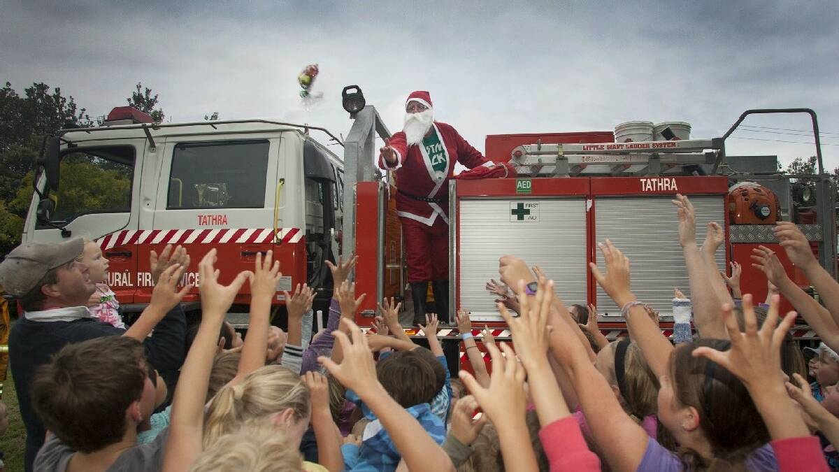 TATHRA: Children reach out for lolly   bags lobbed by Santa at the Tathra Community   Carols night.
