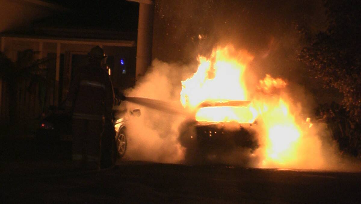 BLAZING: Fire fighters from Fire and Rescue battle the car fire outside a home in Ulladulla on Sunday night. Photo: Gama Video Productions.