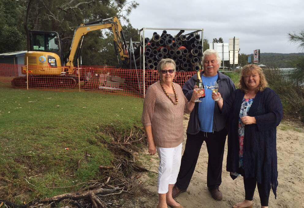 UNDERWAY: Robyn Kerves, Col Ashford and Cr Patricia White celebrate the start of the Conjola dredge project by opening a bottle of bubbles on the shoreline.