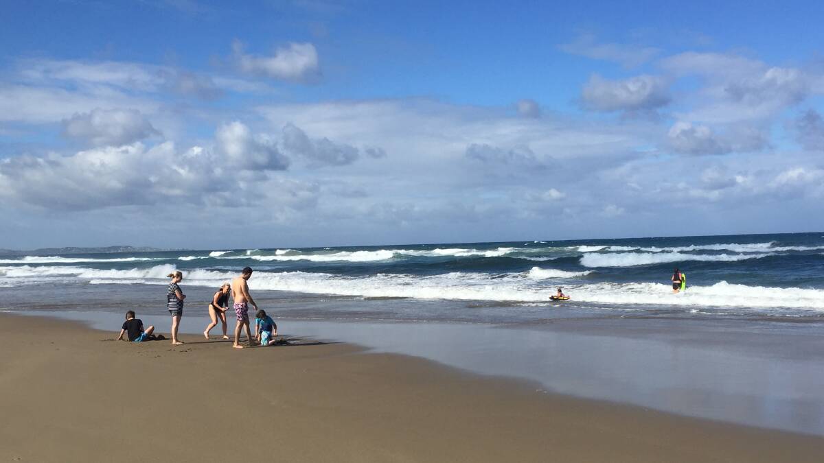 Families play in the shallows at Seven Mile Beach, Shoalhaven Heads on Saturday.