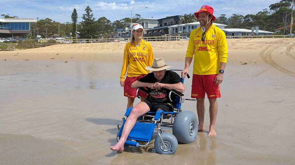 Garry Bradley (front) enjoying the surf, salt and sand with the help of Mollymook Surf Lifesavers Lara and James.