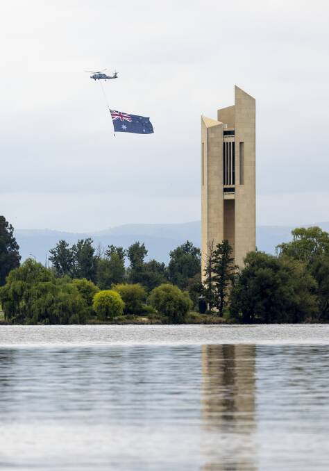 CAPITAL PERFORMANCE: A Royal Australian Navy MH-60R Romeo Seahawk helicopter from 816 Squadron at HMAS Albatross flies over the National Corillon during the 2022 Australia Day ceremony in Canberra. Photo: Julie Whitewell