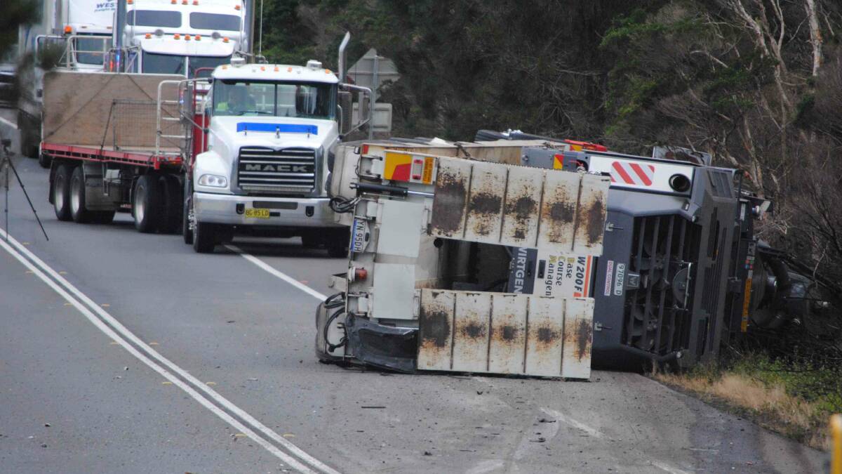 CRASH: The semi-trailer low-loader, carrying road working machinery, came to rest on its side after a fatal accident on the Princes Highway at Bewong. Photo: Damian McGill