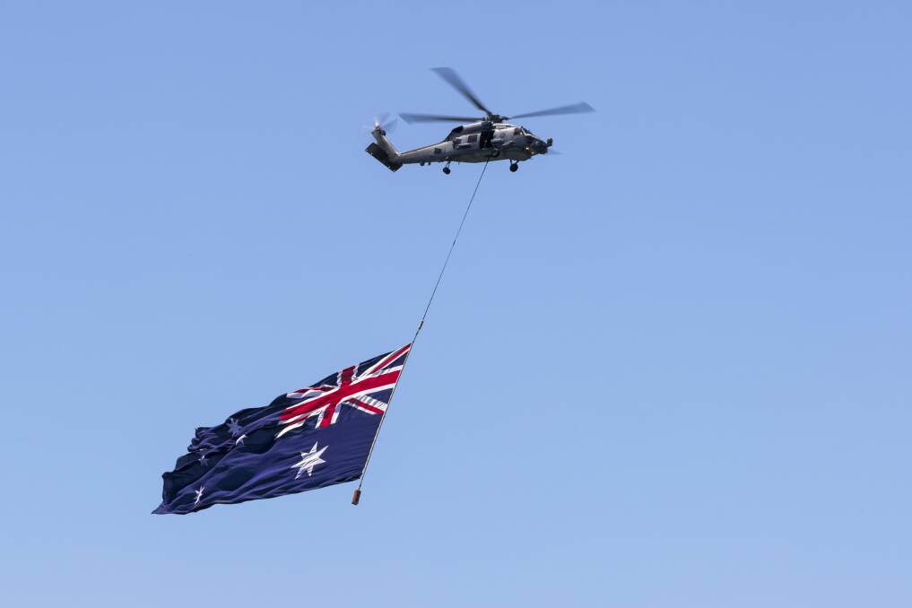 SPECTACULAR: A Royal Australian Navy MH-60R Romeo Seahawk helicopter from 816 Squadron at HMAS Albatross flies with an underslung Australian National Flag during Australia Day celebrations. Photo: Benjamin Ricketts