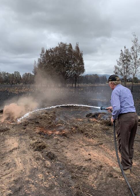 SPOTFIRE: Merv uses a water hose to put out a spotfire.
