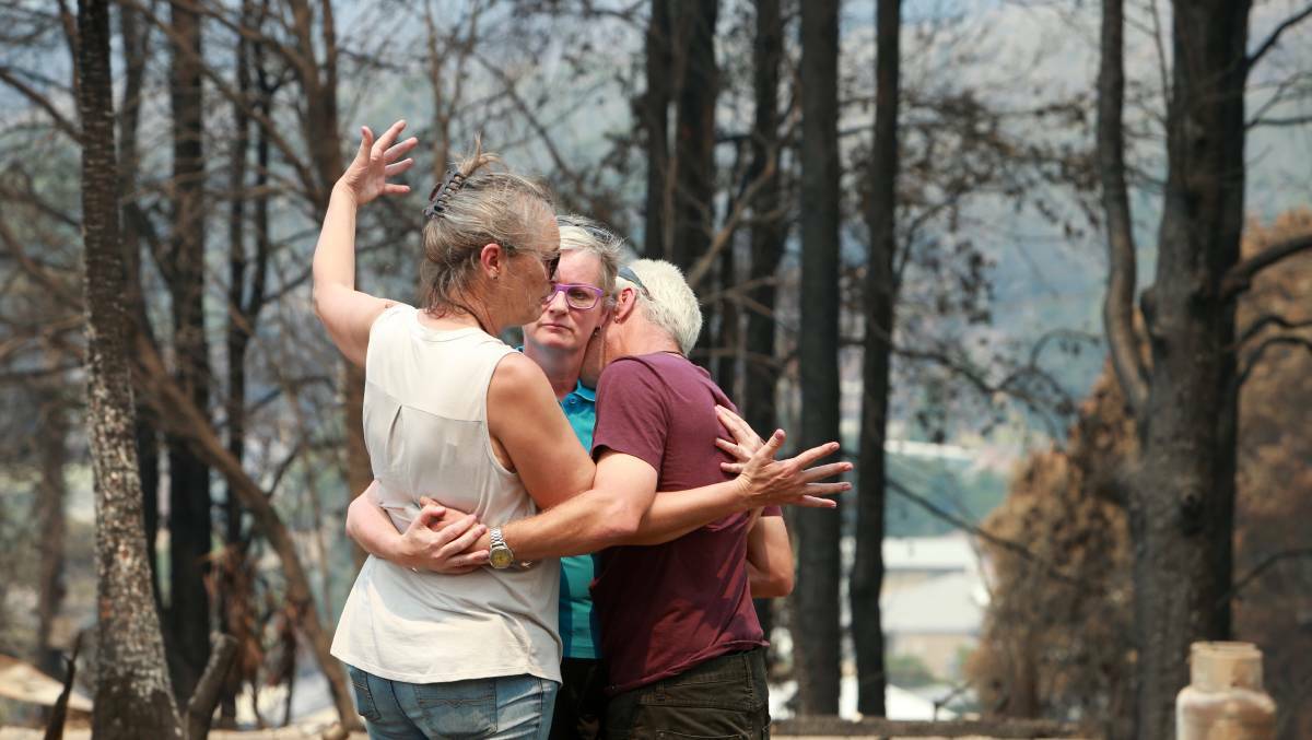 Shoalhaven Mayor Amanda Findley comforts Adam and Chris Webb at Conjola Park on the South Coast of NSW, where 89 homes were lost on New Year's Eve, 2019.