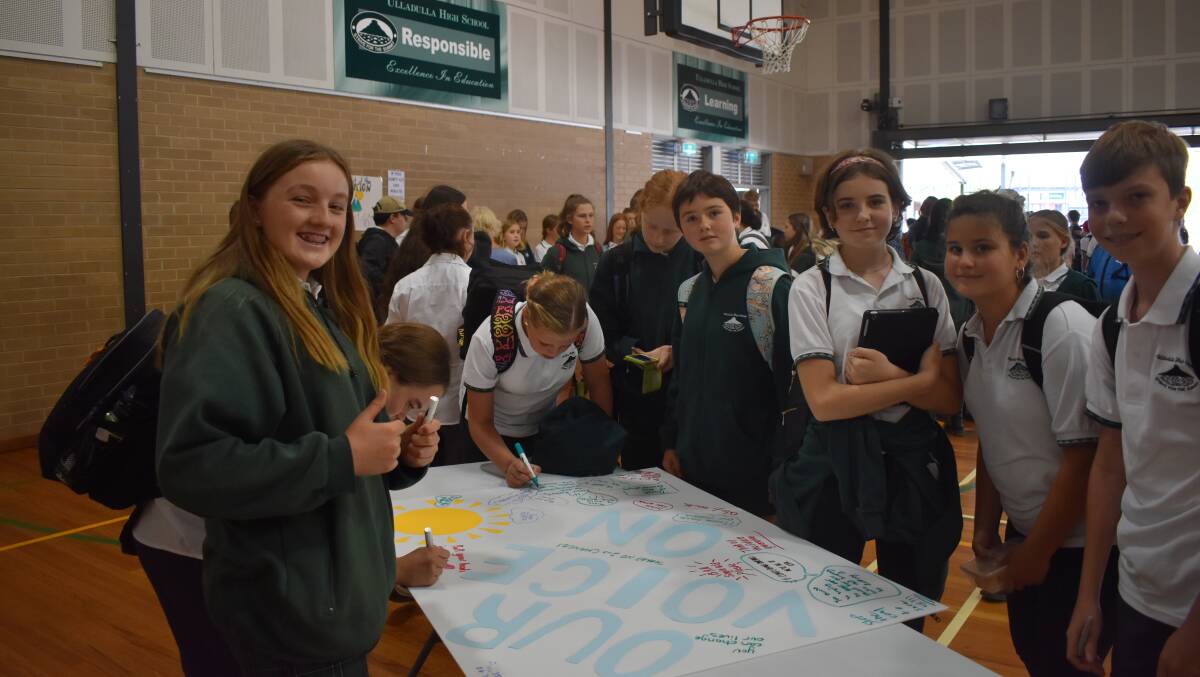 ACTION: Some Ulladulla High School students sign messages to support stronger political action against climate change during their lunchtime rally. Picture: Antonia Bewley.