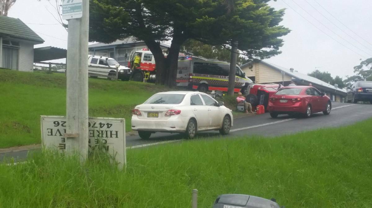 Paramedics treat someone, probably for shock, after a mobile home loses a car on a trailer on Davison Street, Narooma.