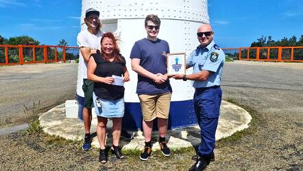 Officer D. Nyholm (right), J.Martin of NSW Mental Health (left), and Ice Schaap (back) representing the Ulladulla Lighthouse Group, thank the designer of the lighthouse logo, Preston Berry. Photo contributed.