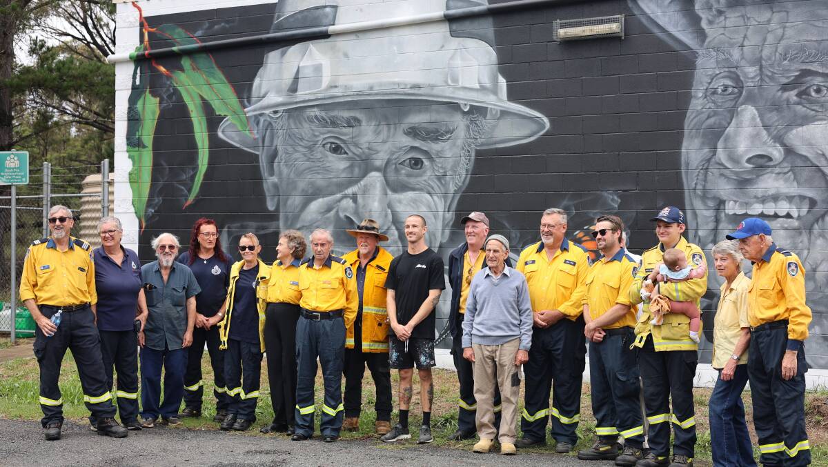 Kiama street artist Samuel Hall with his latest mural and the two volunteer firefighters, Brian Coates and John Matters, who were the subject of the artwork, and other brigade members. Picture by Erin Olafson
