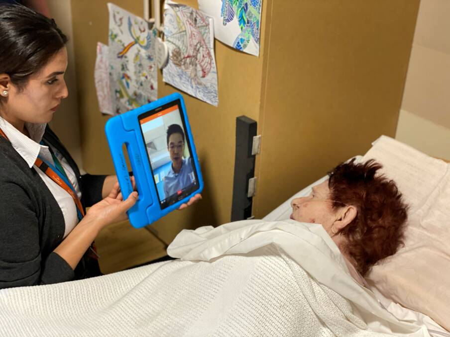 IRT Registered Nurse Sajana Giri holds up a device with the IRT Connect app so that aged care resident Helen Lee can speak with her Doctor, Dr Teh